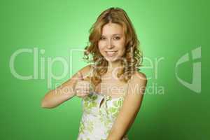 Beautiful woman on green background. Thumbs up
