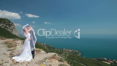 bride and groom on a cliff against blue sky
