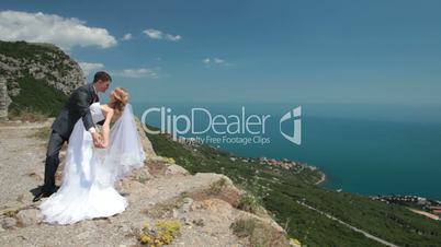 bride and groom on a cliff against blue sky
