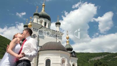 bride and groom kissing near the church