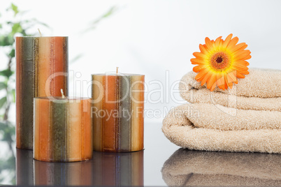 Unlighted candles with an orange gerbera on towels