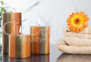 Lighted candles with an orange gerbera on towels
