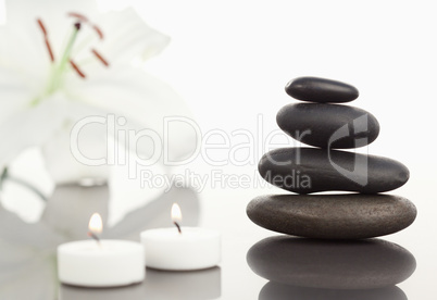 White orchid with lighted white candles and a black pebbles stac