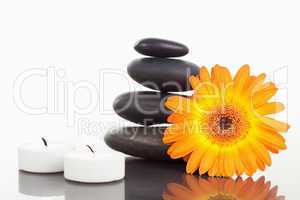 Unlighted candles pebble stack an orange gerbera