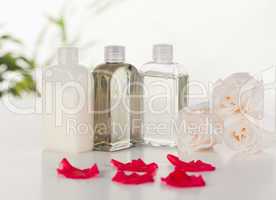 Glass flasks with white roses and pink petals