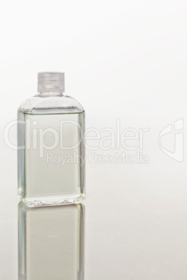 Glass flask on a mirror against white background