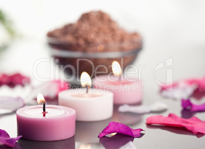 Close up of lighted candles with a brown gravel bowl and petals