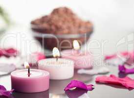 Close up of lighted candles with a brown gravel bowl and petals