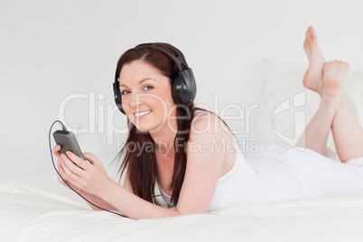 Attractive red-haired female listening to music with her headpho