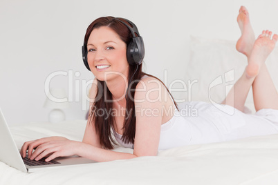 Beautiful red-haired female relaxing with her laptop and her hea