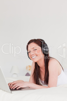 Gorgeous red-haired female relaxing with her laptop and her head