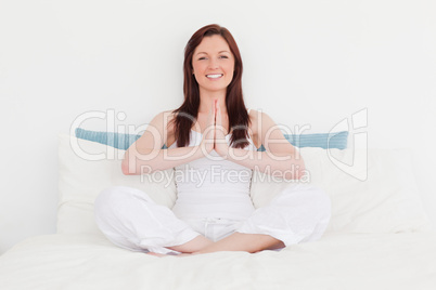 Beautiful red-haired female relaxing while sitting on her bed