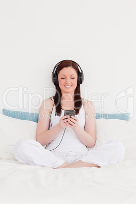 Good looking red-haired woman listening to music with her headph