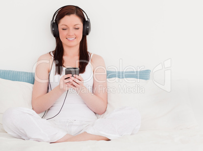 Charming red-haired woman listening to music with her headphones