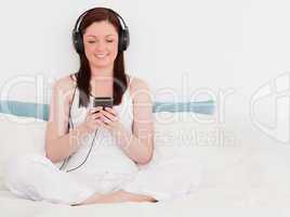 Charming red-haired woman listening to music with her headphones