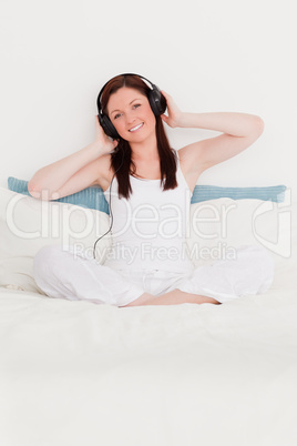 Cute red-haired woman listening to music with her headphones whi
