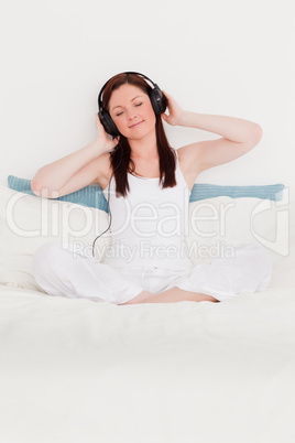 Gorgeous red-haired woman listening to music with her headphones