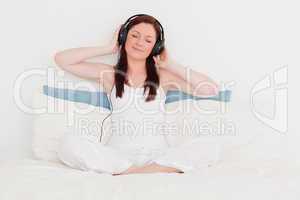 Happy red-haired woman listening to music with her headphones wh
