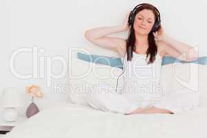 Gorgeous red-haired woman listening to music with her headphones