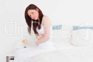Sick red-haired female posing while sitting on her bed