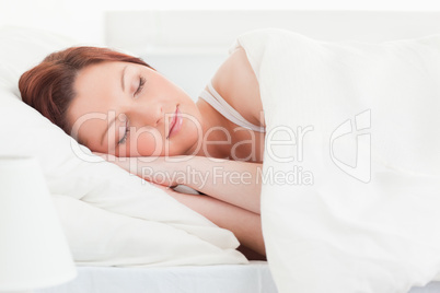 Close-up of a good looking red-haired woman sleeping in her bed