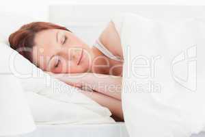 Close-up of a good looking red-haired woman sleeping in her bed