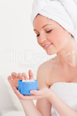 Good looking young woman wrapped in a towel using skin cream