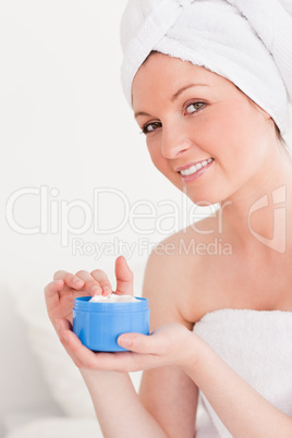 Gorgeous young woman wrapped in a towel using skin cream