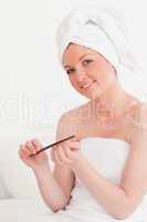 Beautiful young woman wearing a towel using a nail file