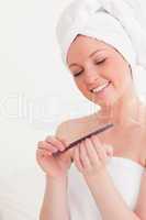 Good looking young woman wearing a towel using a nail file