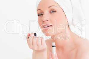 Attractive young woman wearing a towel using a lip gloss