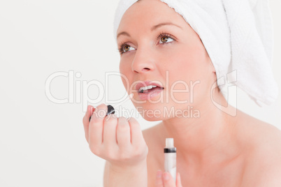 Pretty young woman wearing a towel using a lip gloss