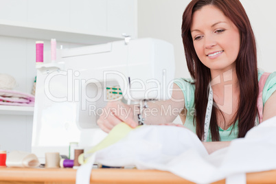 Pretty red-haired female sewing in the living room