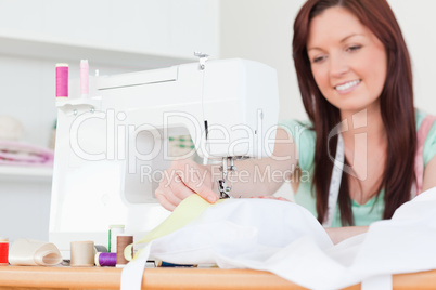 Attractive red-haired female sewing in the living room