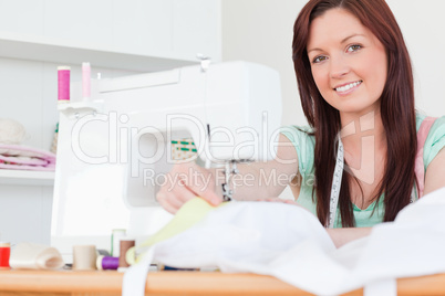 Beautiful red-haired female sewing in the living room