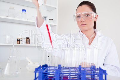 Beautiful female biologist holding a manual pipette with sample