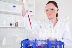 Attractive female biologist holding a manual pipette with sample