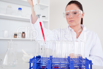 Pretty female biologist holding a manual pipette with sample fro
