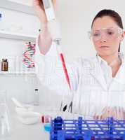 Gorgeous female biologist holding a manual pipette with sample f