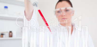Beautiful red-haired scientist filling up a test tube