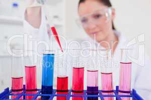 Beautiful female biologist holding a manual pipette with sample