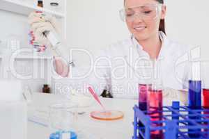 Pretty red-haired scientist using a pipette