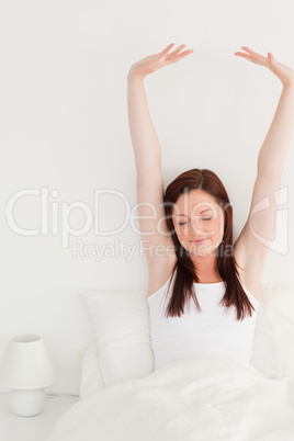 Good looking red-haired female stretching in her bed