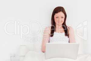 Good looking red-haired woman relaxing with her laptop while sit