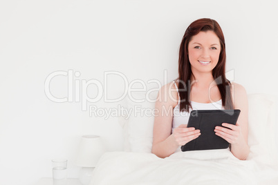 Good looking red-haired woman relaxing with her tablet while sit