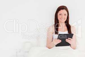 Good looking red-haired woman relaxing with her tablet while sit