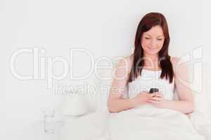 Attractive red-haired woman writing a text on her mobile while s