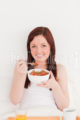 Gorgeous red-haired female having her breakfast while sitting on