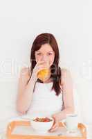 Good looking red-haired female drinking a glass of orange juice