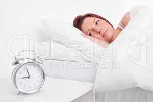 Charming red-haired female waking up thanks to an alarm clock